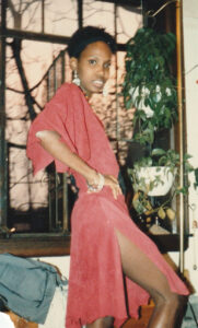 Sherie wearing red chamois dress with black leather inserts, showing the side.
